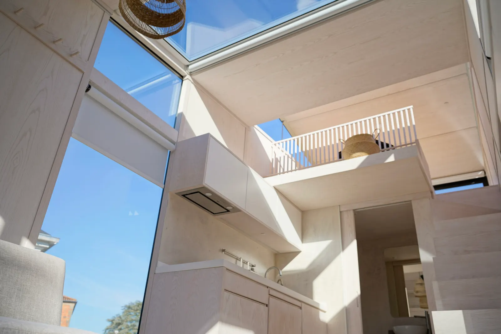 Intérieur blanc d'un module Hoummi baigné de lumière : verrière zénithale au-dessus de la mezzanine et grandes baies