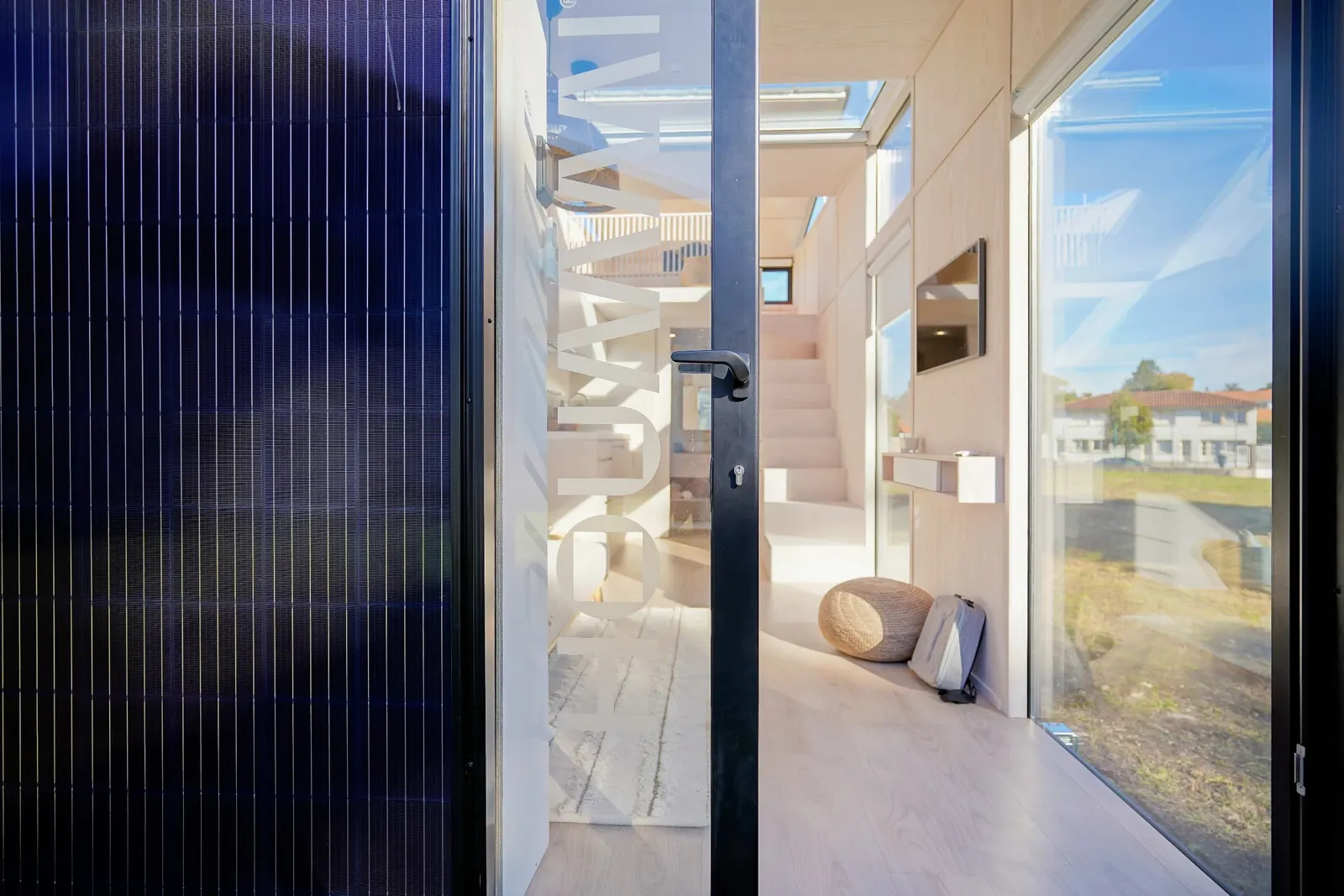 Intérieur d'un module Hoummi vu depuis la porte vitrée : séjour clair, mezzanine et grandes baies